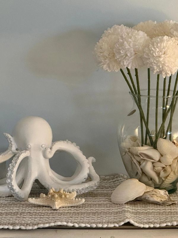 Decorative white octopus figurine and vase with flowers and seashells.