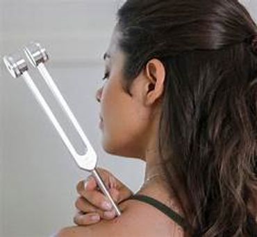 Woman using a tuning fork on her shoulder for therapy.