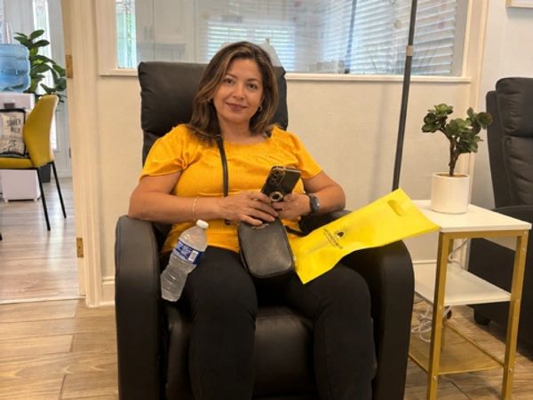A smiling patient seated in a treatment chair receiving amino acid support care