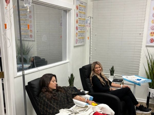Two patients seated side by side receiving IV therapy in reclining chairs