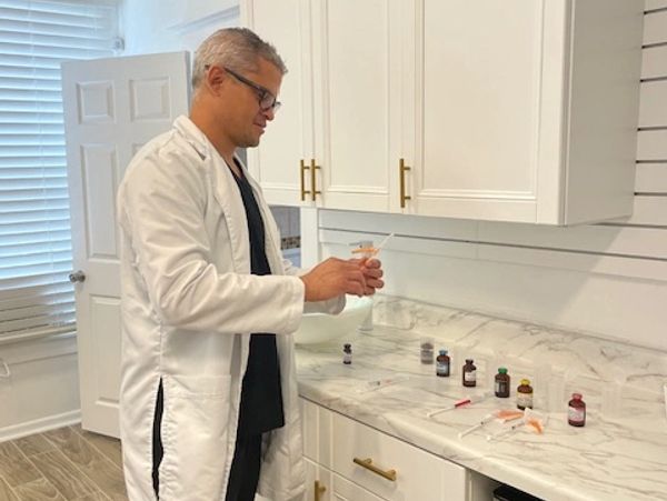 A healthcare provider preparing wellness therapy solutions at a clinic counter