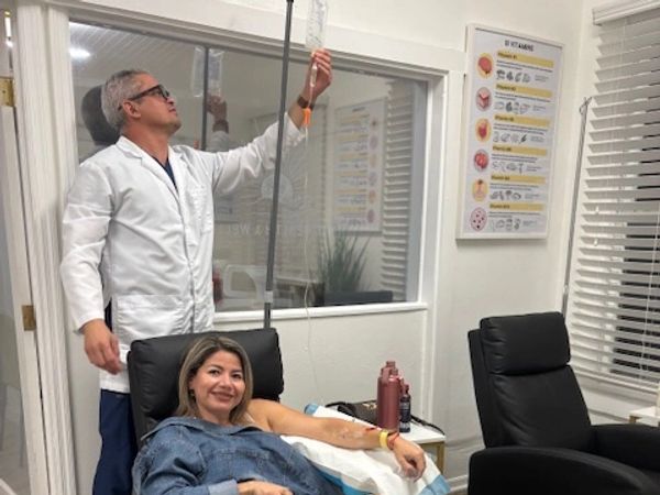 Healthcare provider monitoring an IV infusion for a female patient receiving nutritional support at 