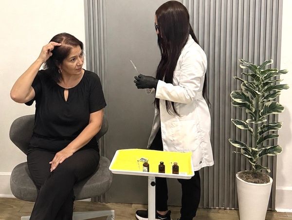 A provider examining a patient's scalp and hair during a consultation