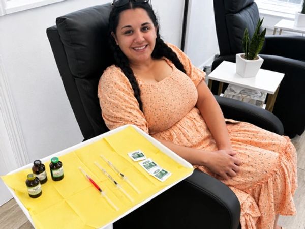 A smiling patient seated comfortably in a treatment chair during a wellness injection visit