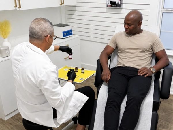 A provider administering treatment to a seated male patient in an exam room