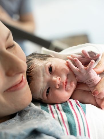 A mother lovingly holds her newborn baby moments after birth.