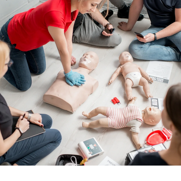 A group practicing CPR on adult and infant mannequins during a training session.
