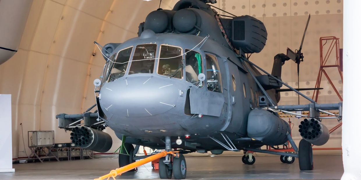 Military helicopter inside government aircraft hangar during maintenance inspection.