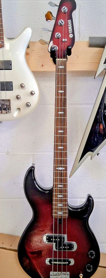 Vintage Yamaha electric bass guitar with sunburst finish hanging on a wall.