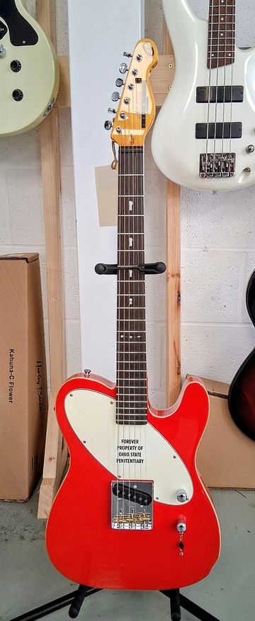 Red electric guitar with "FOREVER PROPERTY OF OHIO STATE PENITENTIARY" on the pickguard.