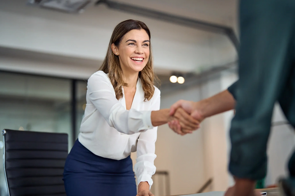 A teacher shaking hands with another man in an office.