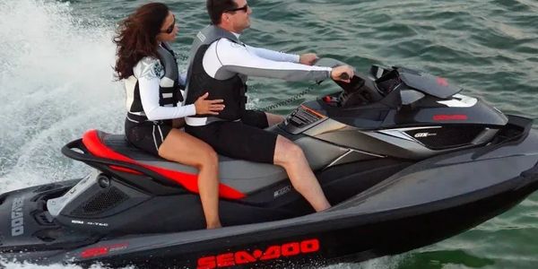 Couple enjoying a ride on a Sea-Doo jet ski over the water.