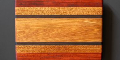 Wooden cutting board with multiple wood tones and dark separator lines.