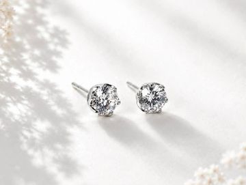 Elegant diamond stud earrings sparkling on a soft white surface.