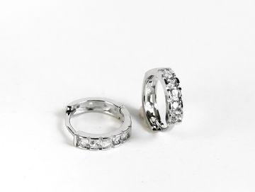 Pair of silver hoop earrings encrusted with small diamonds against white background.