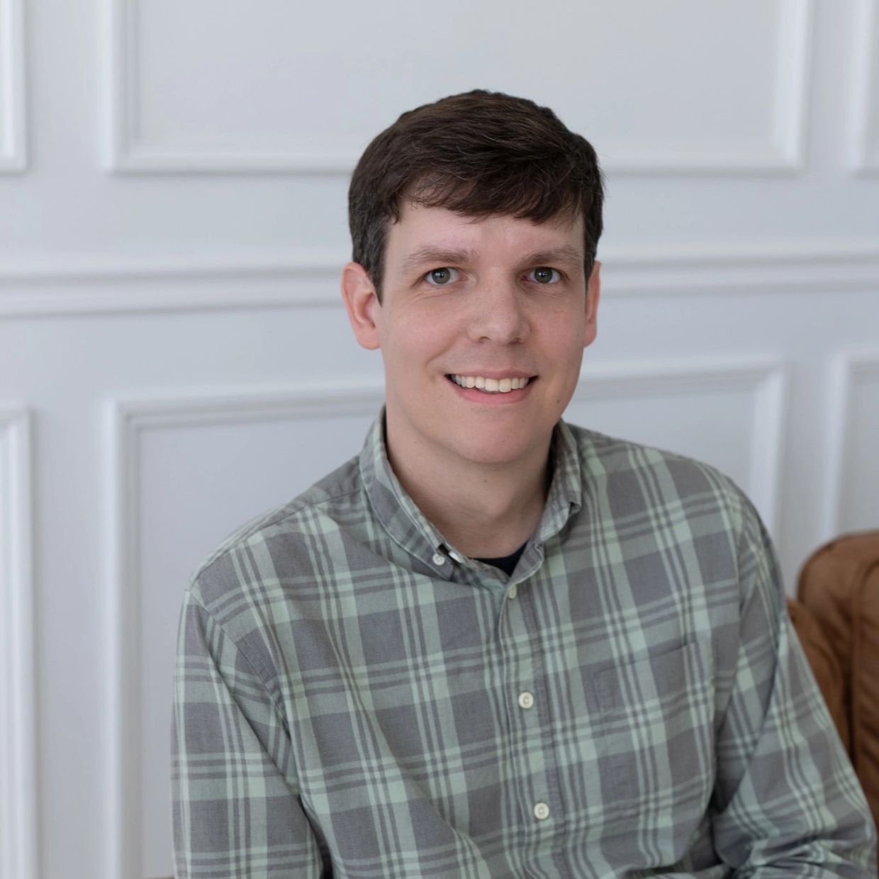 Smiling man wearing a green plaid shirt.
