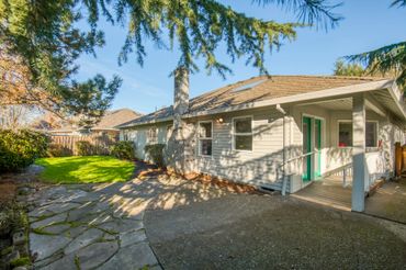 Cozy single-story house with a stone pathway and lush greenery.