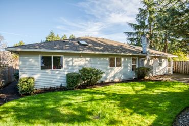 Single-story house with white siding and a green lawn under a partly cloudy sky.