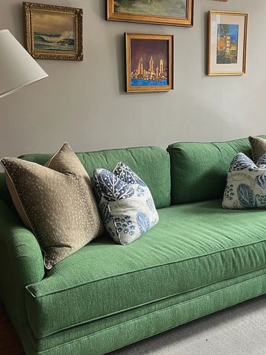 Green sofa with pillows and art wall