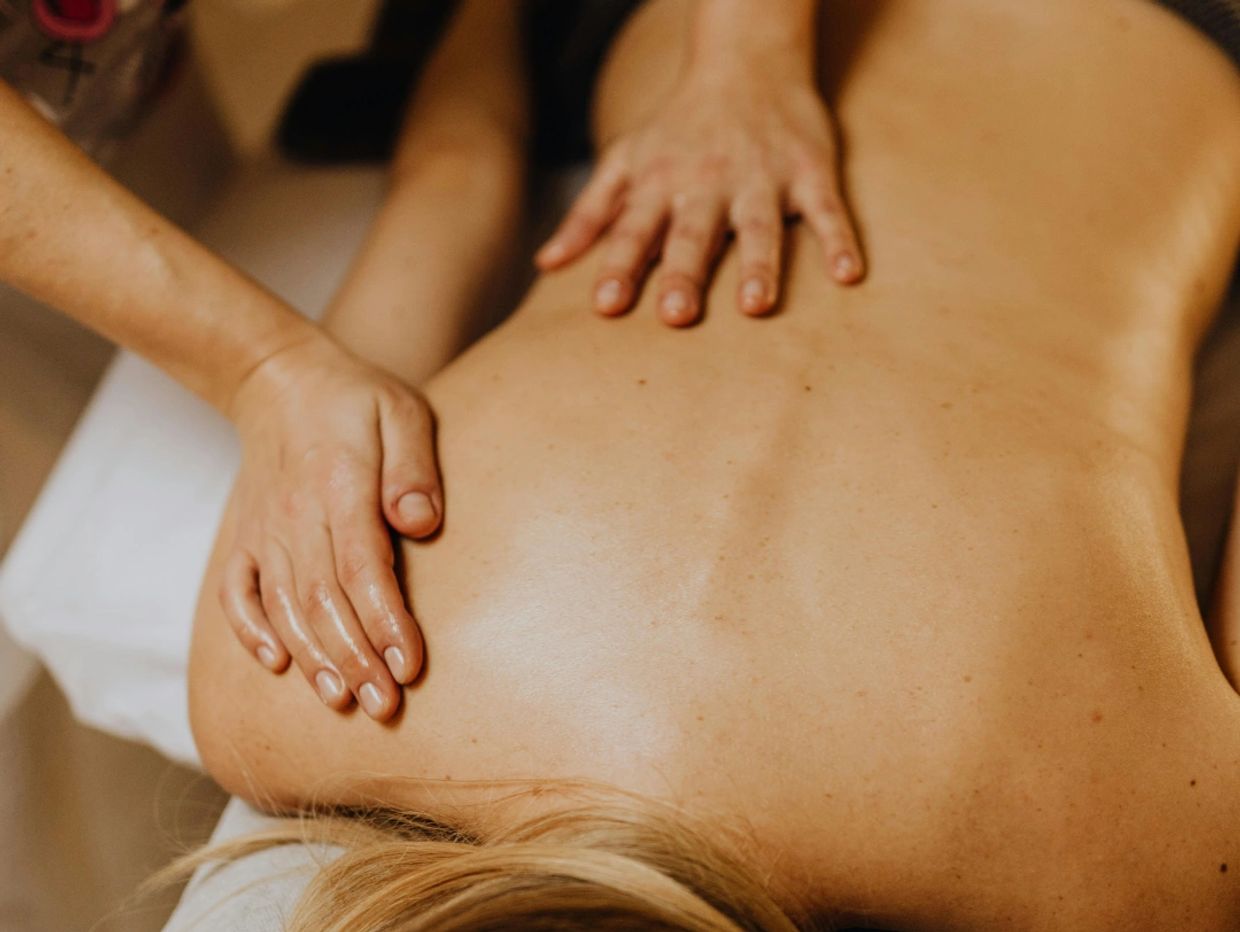 Hands giving a back massage to a person lying face down.