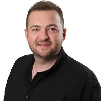 Smiling man in a black shirt against a white background.