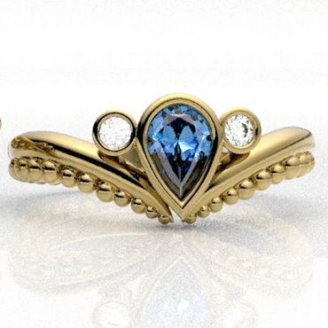 Gold ring with a pear-shaped blue gemstone and two round diamonds.