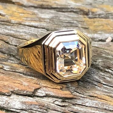 Gold ring with a large, clear, square-cut gemstone.