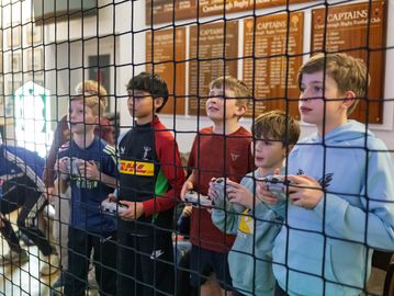 Children playing video games behind a net indoors.