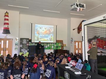 A speaker presents drone education to a group of students in a school assembly.