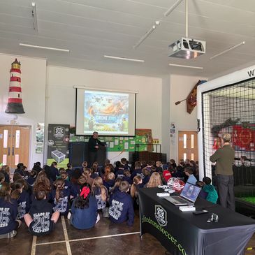 Children seated in a hall listening to a presenter about drones.