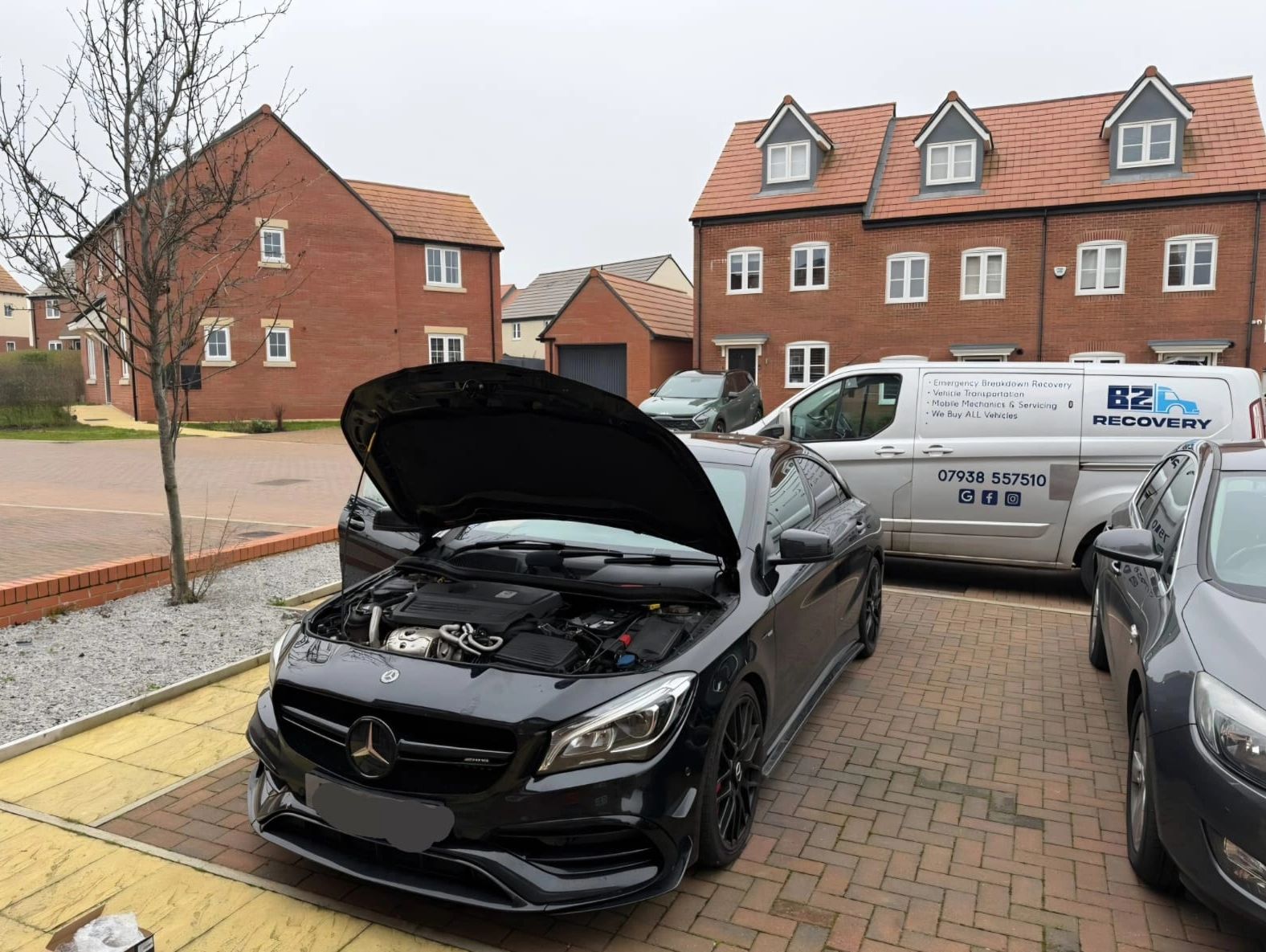 Black Mercedes with open hood parked in a suburban driveway.