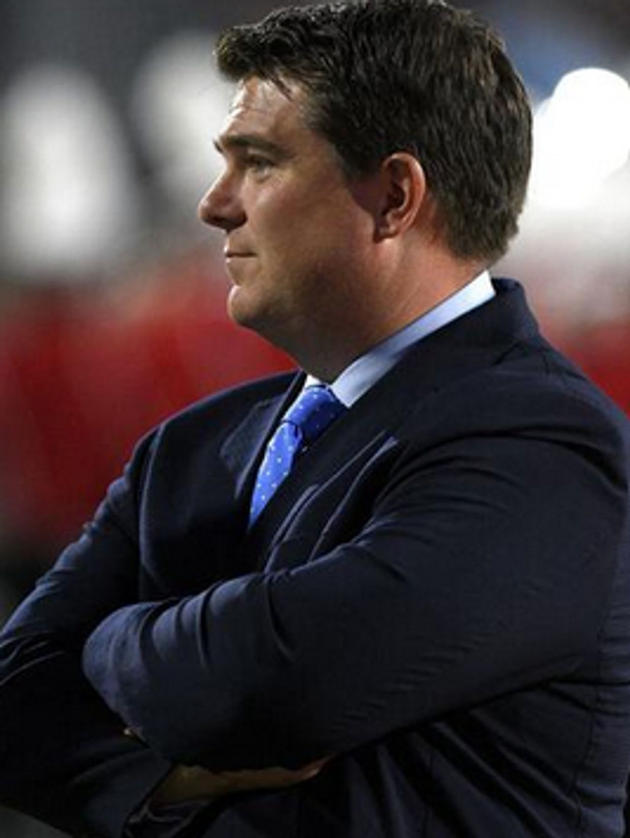 Man in suit with arms crossed, looking to the side.