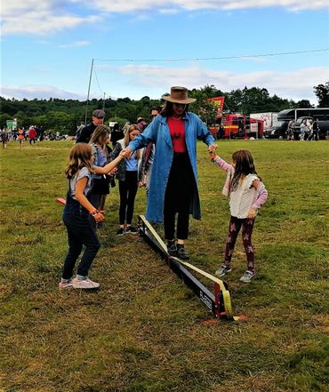 two small children helping their mum walk along a slackrack