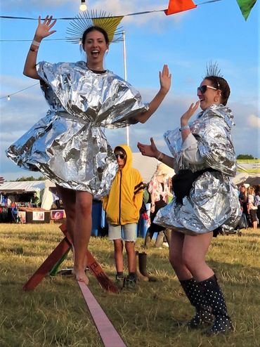 two friends dressed in silver attempting to slackline