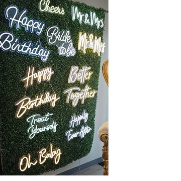 Neon signs with celebratory phrases on a green wall.