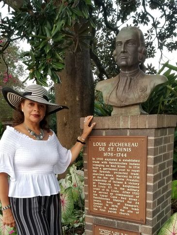 Woman posing beside a Louis Juchereau de St. Denis monument.