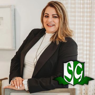 Confident woman in black blazer smiling indoors.