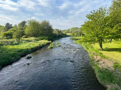A scenic river flowing through lush greenery under a partly cloudy sky.