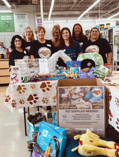 Group of volunteers collecting pet supplies for donation at a store.