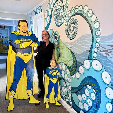 Woman posing with superhero cutouts and octopus mural.