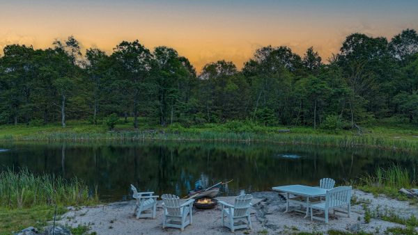 Campfire seating area by a peaceful lakeside at sunset.