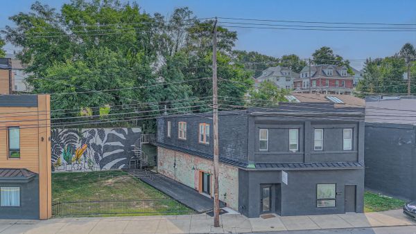Urban building with dark exterior and mural on adjacent wall.