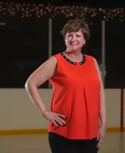 Smiling woman posing in an orange top.