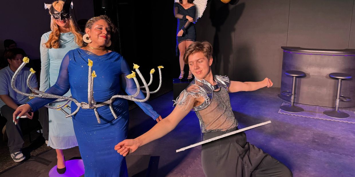 People in creative costumes performing on stage with dramatic poses.
