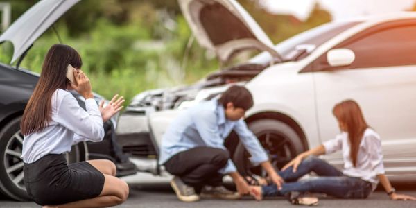 Woman calls for help while others assist injured woman after car accident.