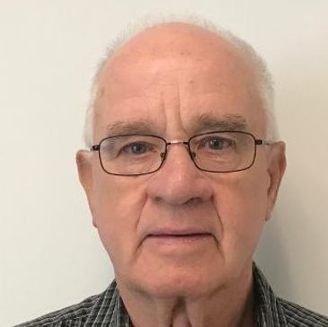 Portrait of an elderly man wearing glasses and a checkered shirt.