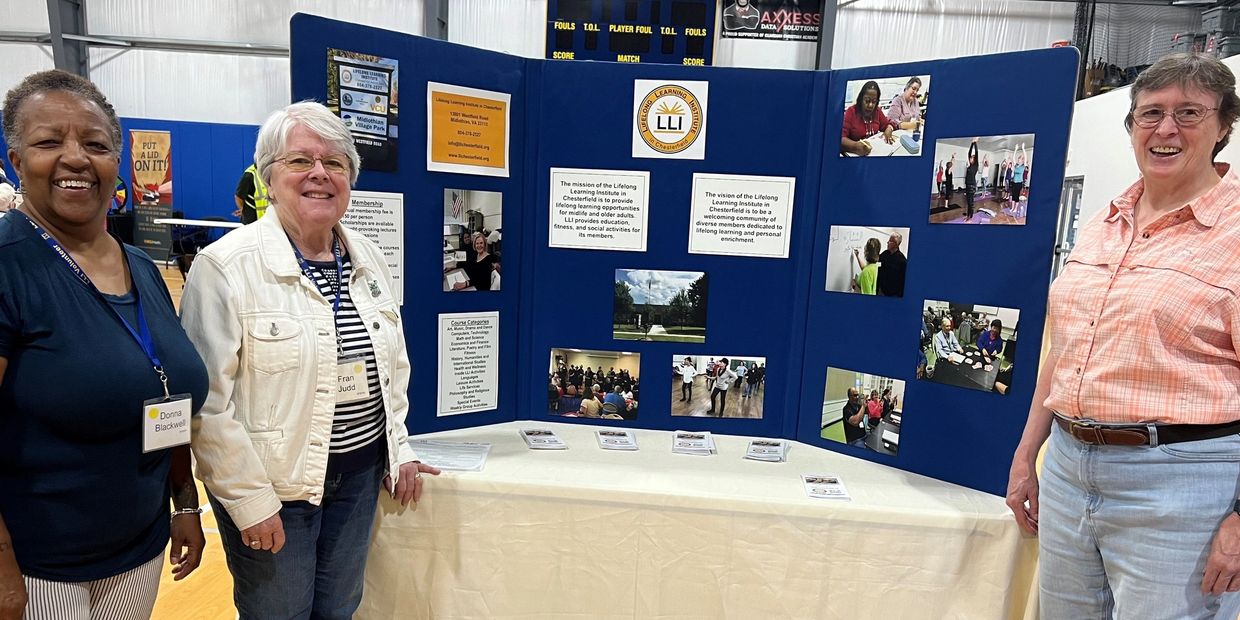 Donna Blackwell, Fran Judd, and Diane Steer standing with the LLI Booth at a local event.