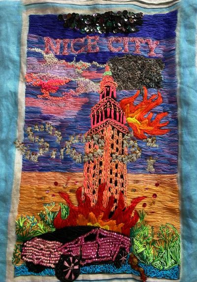 Colorful embroidery of a city tower, flames, and a car with 'NICE CITY' text.