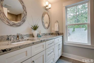 Modern bathroom with double sinks, granite countertop, and round mirrors.