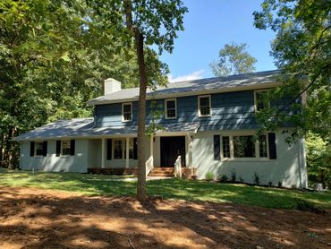 A spacious two-story house surrounded by trees and greenery.